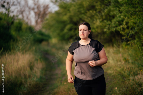 Weight loss, outdoor activity, exercising, healthy lifestyle, jogging. Overweight woman running on summer meadow