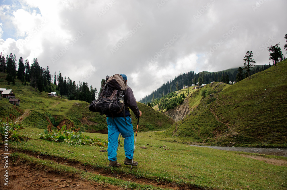 Male tourist with backpack stands near the river