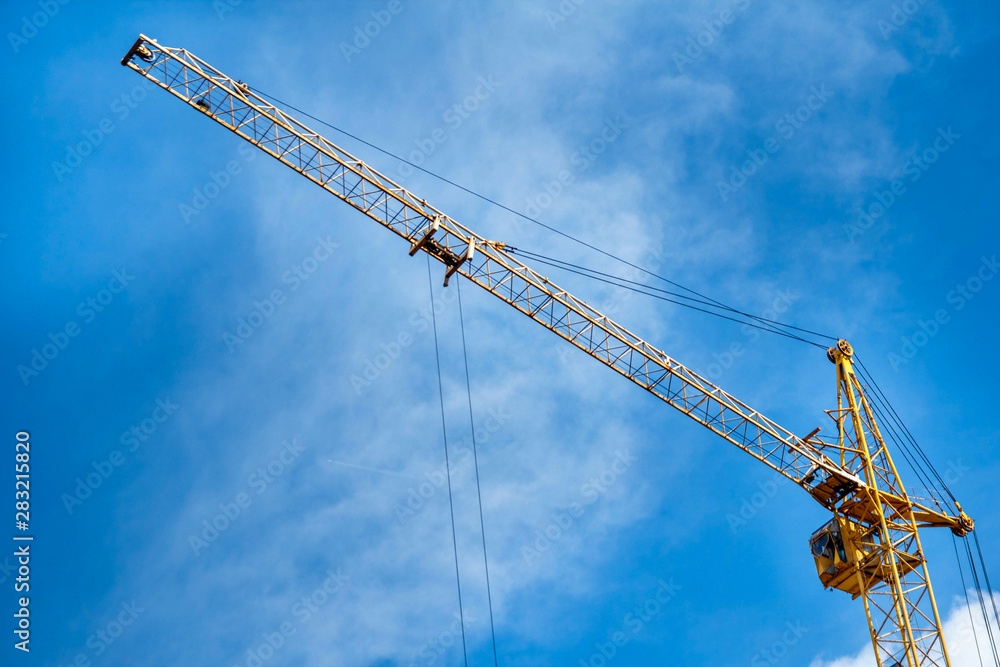 Construction yellow crane against the background of a blu sky