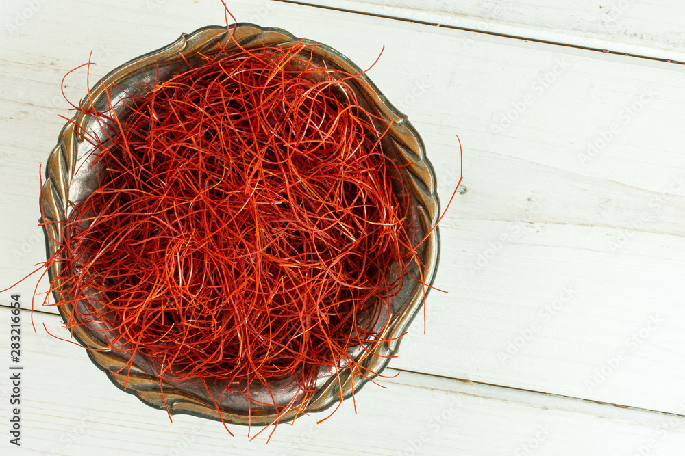 Fototapeta premium Lot of whole red chili pepper threads in old iron bowl flatlay on white wood