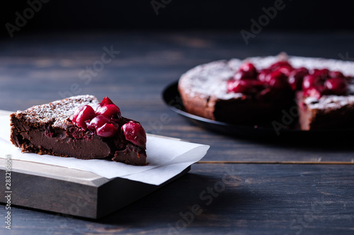 A slice of chocolate clafouti with a cherry on a wooden table. French delicious dessert. photo