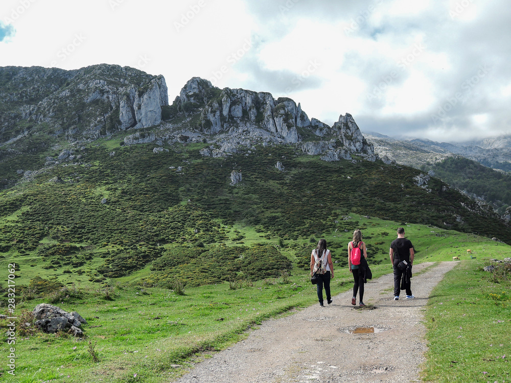 Three people walking on a dirt path in Asturias, Spain