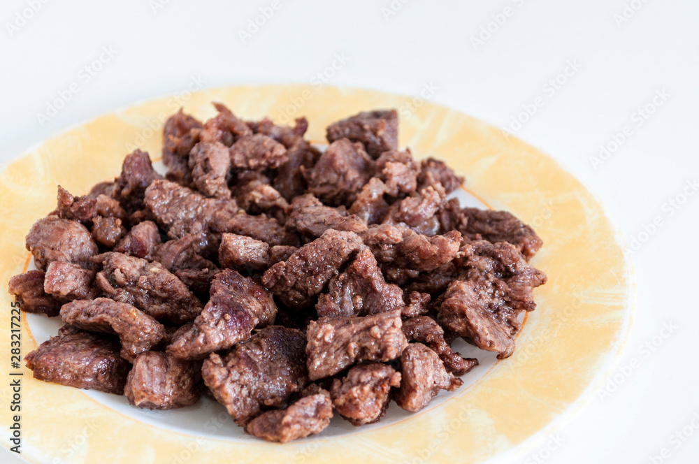 Perspective close-up shoot of tasty meat on small plate with white background Perspective close-up shoot of tasty meat on small plate with white background