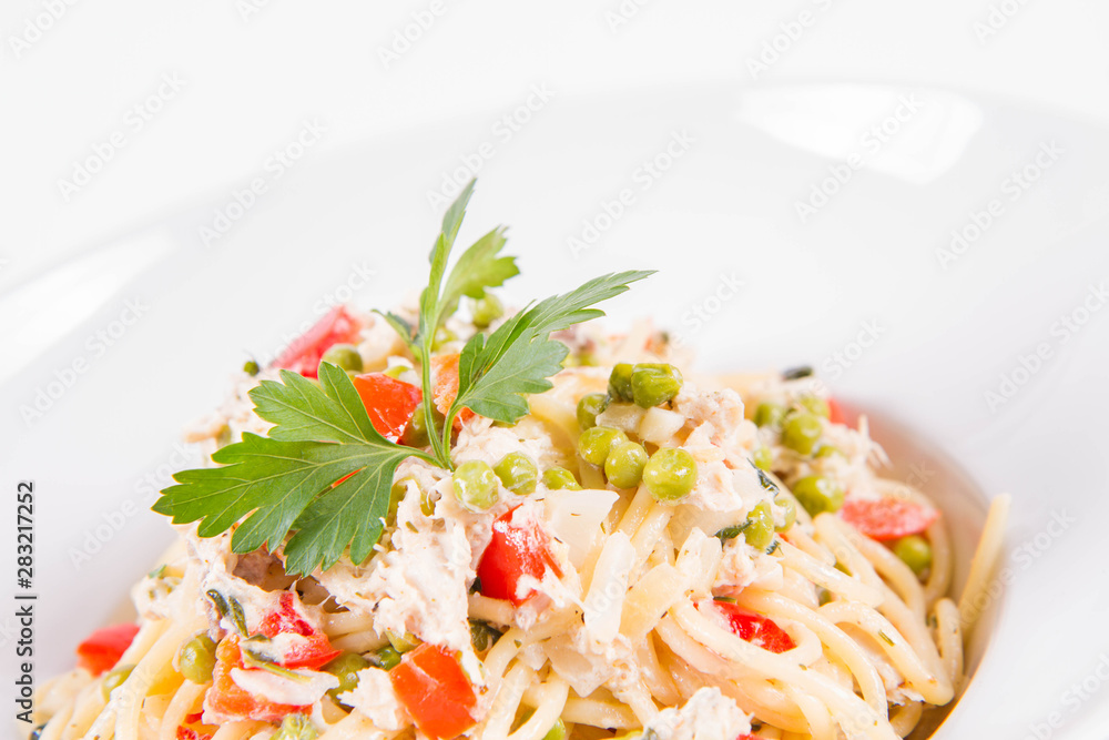 Spaghetti with cream sauce with smoked mackerel, peas ,bell pepper and some parsley on a white plate on a white background Spaghetti with cream sauce with smoked mackerel, peas ,bell pepper and some parsley on a white plate on a white background