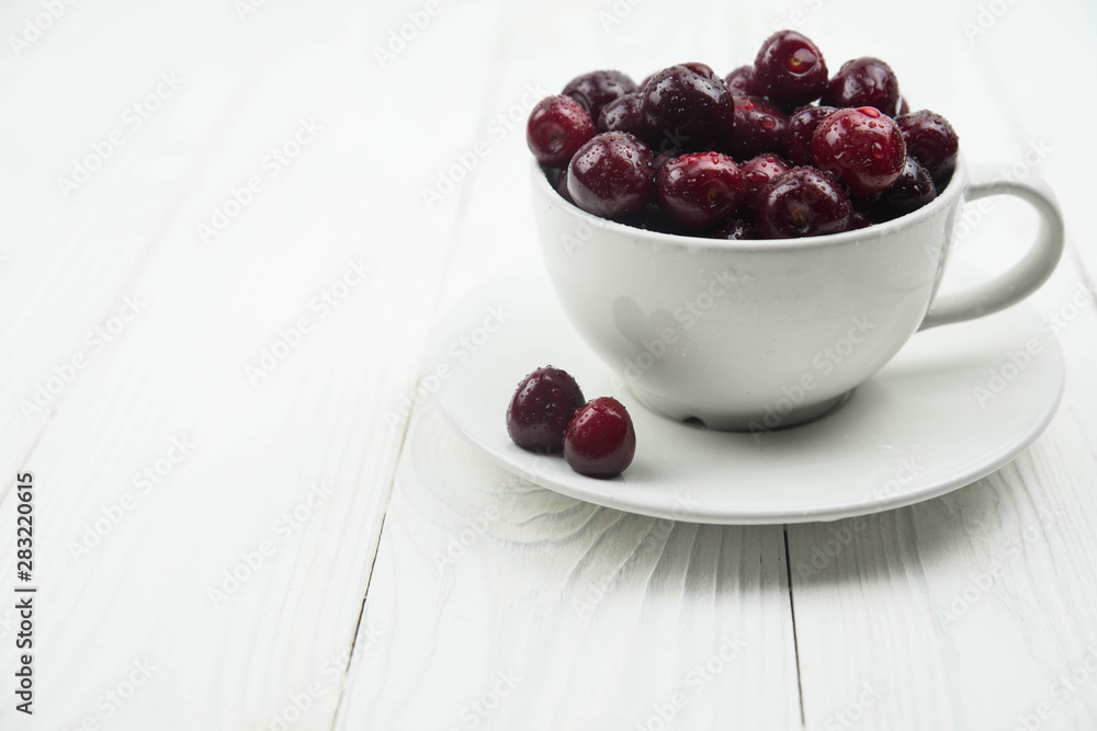A lot of fresh sweet cherry fruit berries with water drops, close up in tea cup on white background. Close up of pile of ripe cherries. Large collection of fresh red cherries. Ripe cherries texture A lot of fresh sweet cherry fruit berries with water drops, close up in tea cup on white background. Close up of pile of ripe cherries. Large collection of fresh red cherries. Ripe cherries texture