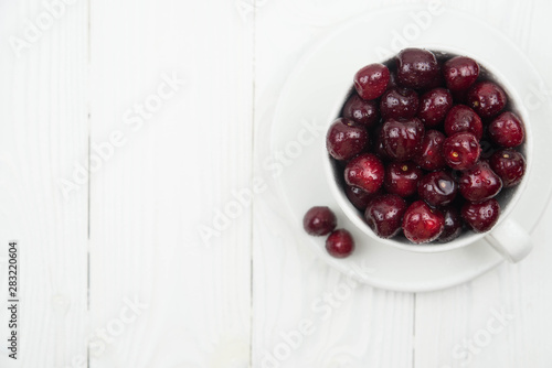 Fototapeta Naklejka Na Ścianę i Meble -  A lot of fresh sweet cherry fruit berries with water drops, close up in tea cup on white background. Close up of pile of ripe cherries. Large collection of fresh red cherries. Ripe cherries texture