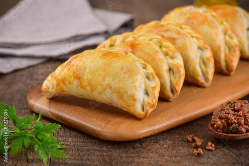 Meat roasted empanas on wooden background