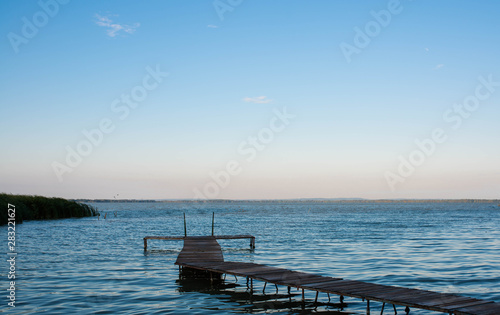 Wood deck over blue Balaton lake in Hungary at a cold morning at summertime, copy space.