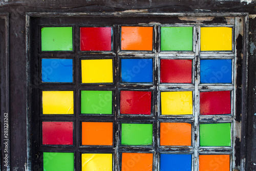 Colorful pieces of glass in pine wood frame on old abandoned house.