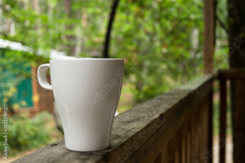  A white mug stands on the railing of the veranda in the morning.