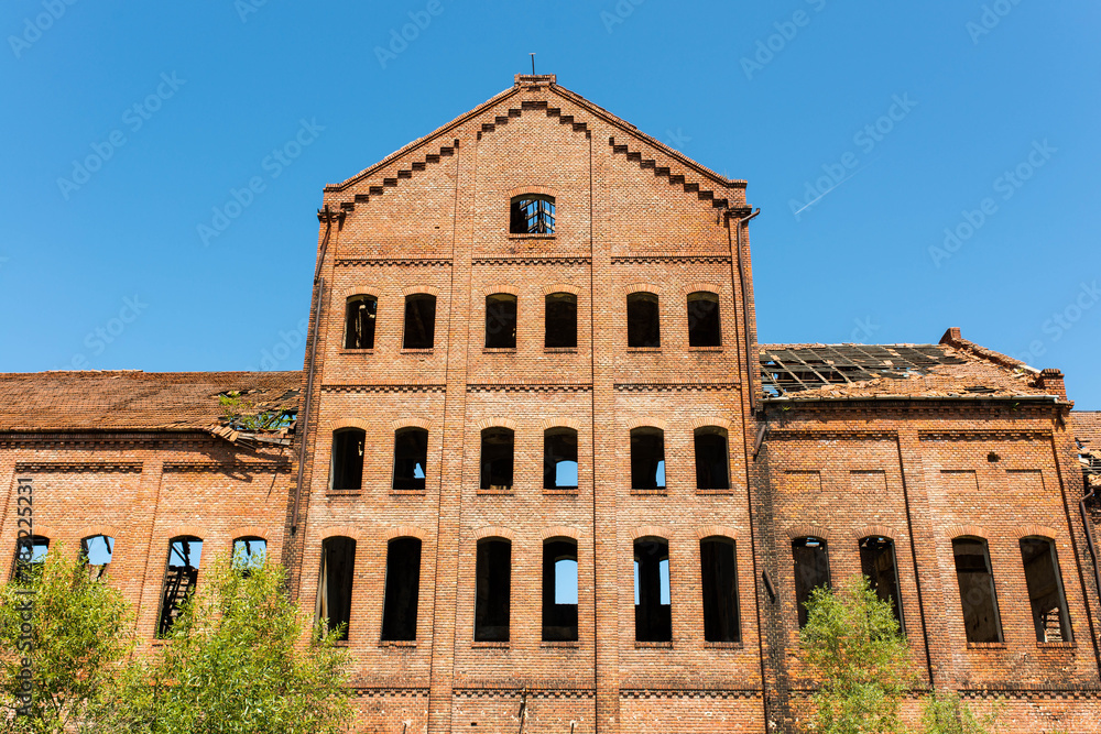 Vertical image of an old abandoned brick factory on a bright sunny day.