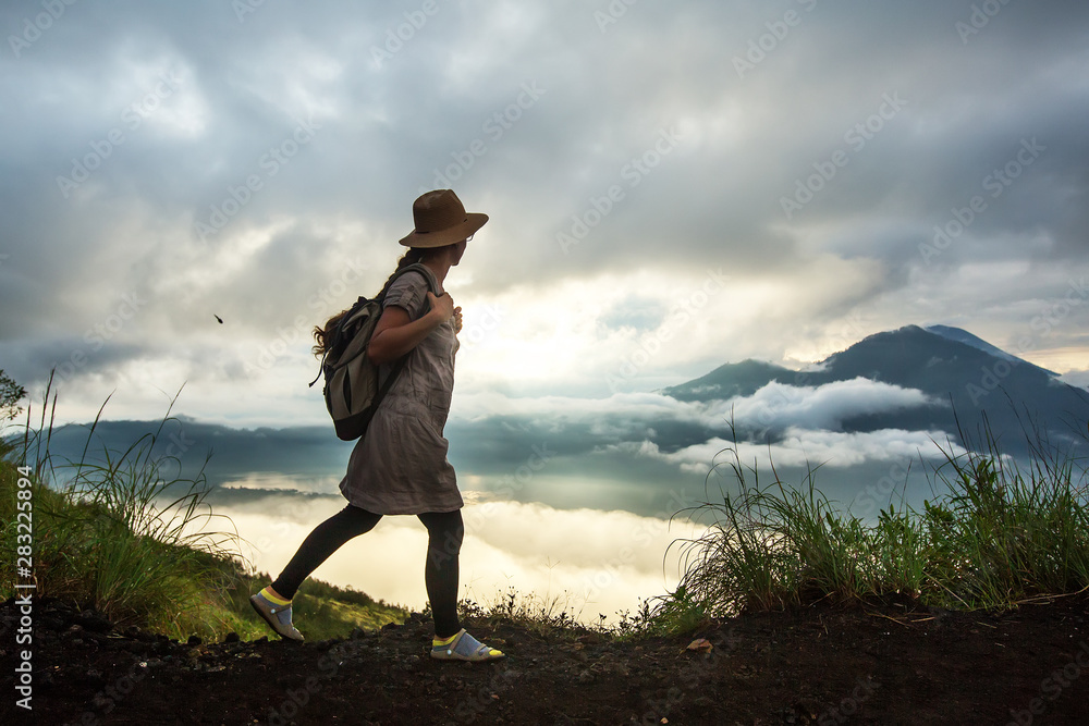 Fototapeta premium Woman enjoying sunrise from a top of mountain Batur, Bali, Indonesia.