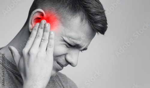 Foto Sick man having ear pain, touching his painful head