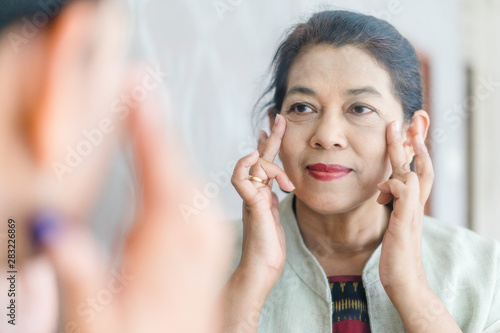Foto Senior Adult Women show her crow's feet on the mirror
