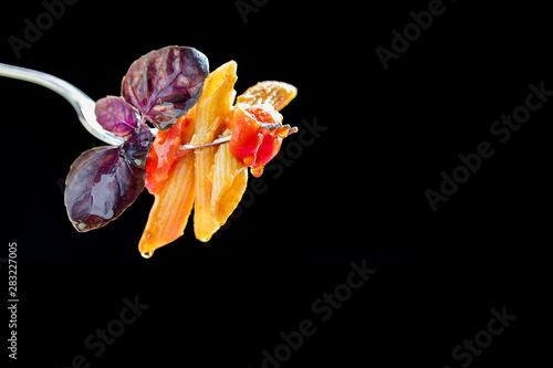 Forkful of pasta with cherry tomatoes and purple basil. Black background and copy space. photo