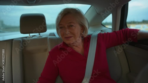 Senior woman in car talk sitting behind happy adventure close up handheld drive customer free time holiday journey smiling summer travel vacation front view slow motion photo