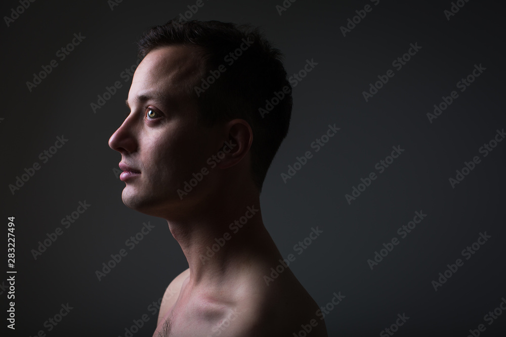 Dark (low key) portrait of a pensive, handsome young man on grey background Dark (low key) portrait of a pensive, handsome young man on grey background