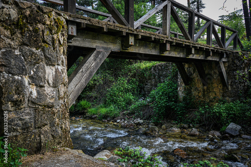 Wooden and stone bridge over the river in the woods