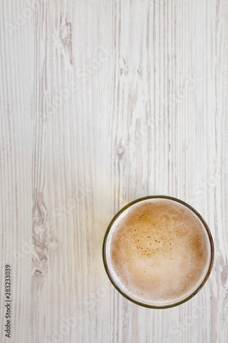Glass of light beer on a white wooden background, top view. Overhead, from above. Copy space. © Liudmyla