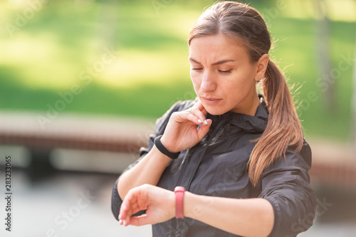 Beautiful sportive girl checking her pulse during fitness exercises, jogging
