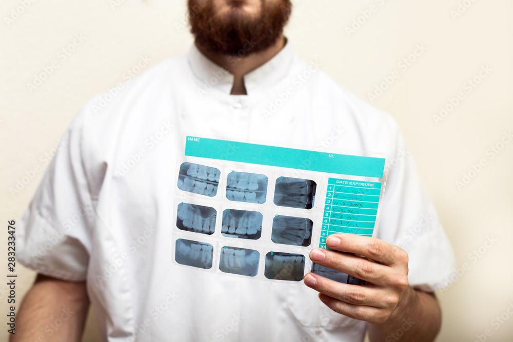 Image of male doctor or dentist holding and looking at old dental x-ray, analyzing Image of male doctor or dentist holding and looking at old dental x-ray, analyzing