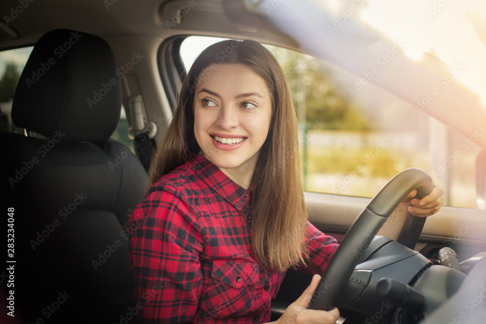 Attractive young woman in casual wear smiling while driving a car 