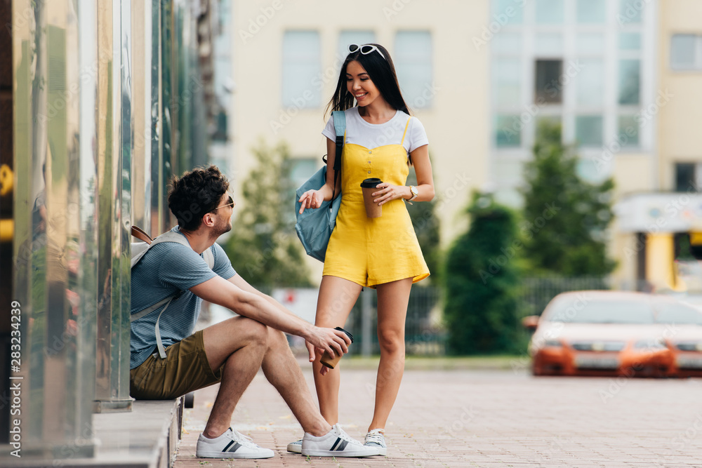 man and asian woman talking and holding paper cups man and asian woman talking and holding paper cups