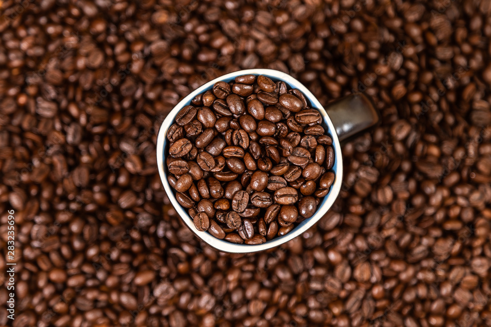 coffee beans background with a coffee mug full of coffee beans. coffee beans background with a coffee mug full of coffee beans.