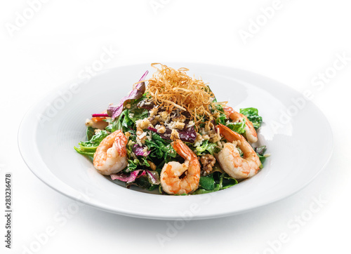 Healthy fresh salad with lettuce, greens, nuts, shrimp and sauce in plate on isolated white background. Healthy food, clean eating, dieting
