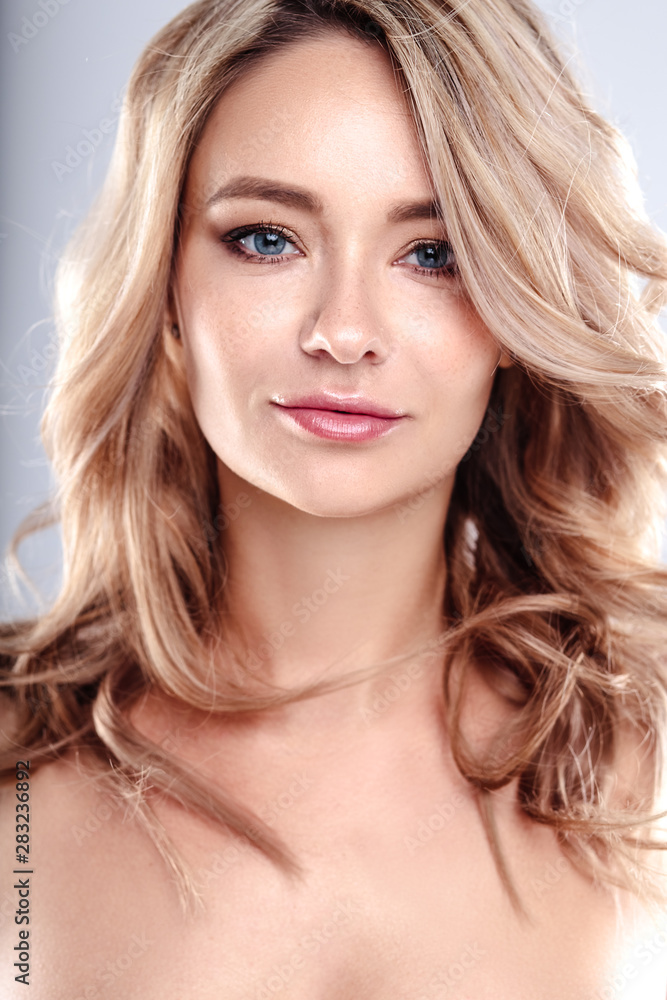 Blonde young woman with healthy curly hair and natural make up . Beautiful model girl with wavy hairstyle. Care and beauty Blonde young woman with healthy curly hair and natural make up . Beautiful model girl with wavy hairstyle. Care and beauty