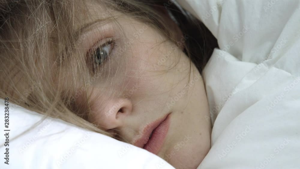 Young woman lying in bed suffering from mental health issues such as depression and anxiety Young woman lying in bed suffering from mental health issues such as depression and anxiety