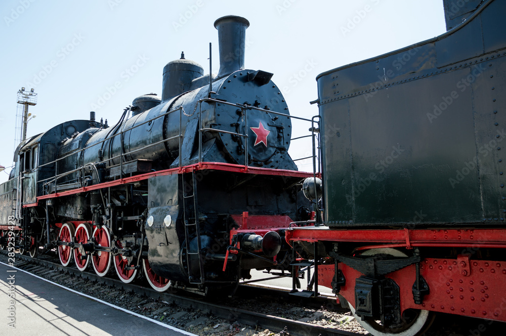 Fototapeta premium Black Soviet locomotive with a red star is on the rails.