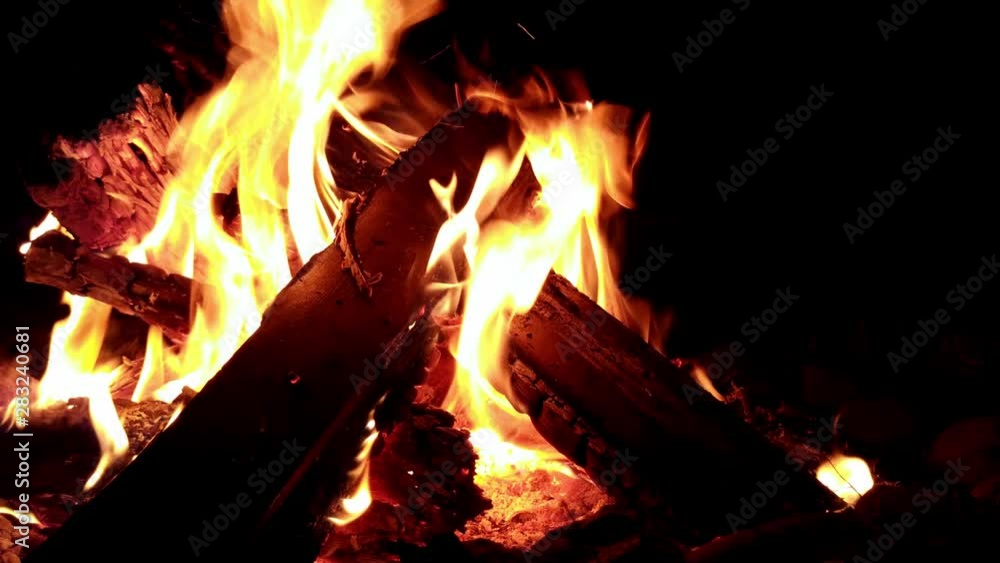 Slow rising view of logs on a campfire with yellow flames roaring out Slow rising view of logs on a campfire with yellow flames roaring out