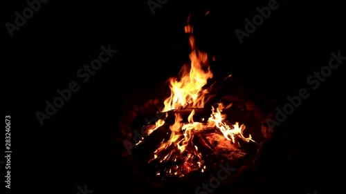 Static timelapse of yellow flames lapping around a bonfire at night photo
