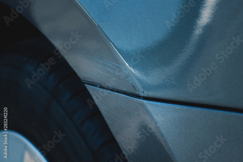 Scuffing on the wing and bumper of the car. Summer, gray car. Close-up.