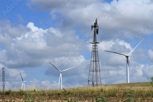 Wind Turbines and a country Windmill on a hill in a pasture