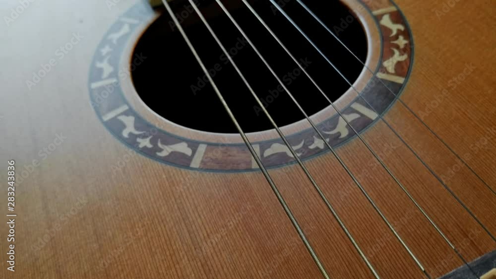 Close-up shot of a bridge, saddle, strings and sound hole in a guitar. Close-up shot of a bridge, saddle, strings and sound hole in a guitar.