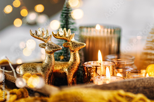 Burning candles and christmas decorations on wooden tray with warm plaid. Winter cozy style. Hygge concept.