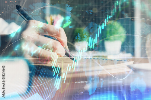 Financial forex charts displayed on woman's hand taking notes background. Concept of research. Double exposure