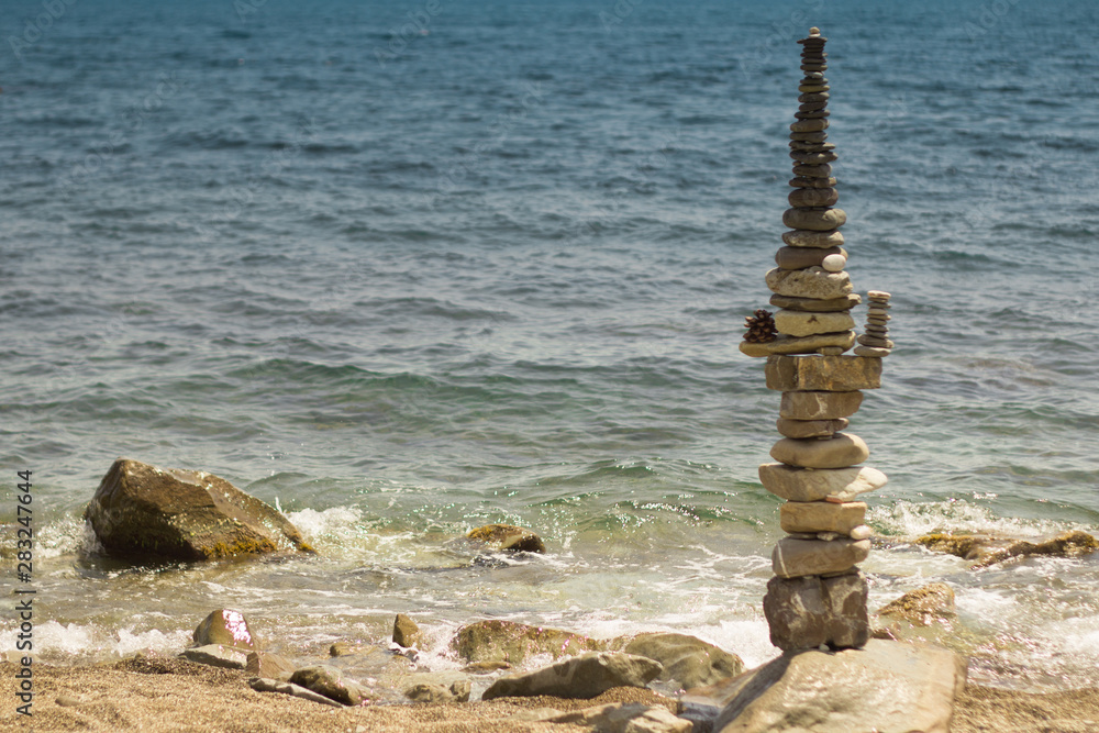 Cairn of pebbles on the black sea. Zen stack of stones with turquoise background. Cairn of pebbles on the black sea. Zen stack of stones with turquoise background.