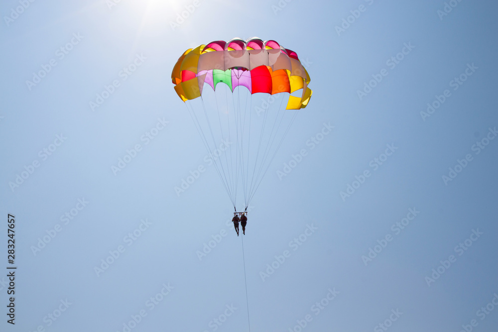 A couple in love fly across the sky on a parachute behind a yacht. A family that loves risky entertainment. Sea holidays in southern countries A couple in love fly across the sky on a parachute behind a yacht. A family that loves risky entertainment. Sea holidays in southern countries
