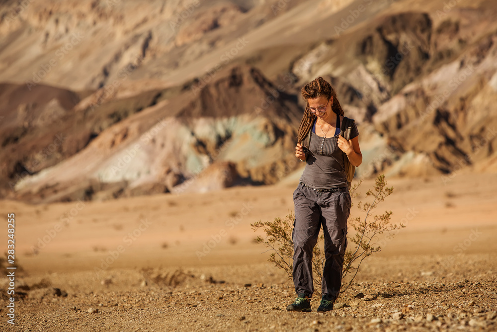 Naklejka premium A hiker in the Artist`s Palette landmark place in Death Valley National Park, Geology, sand.