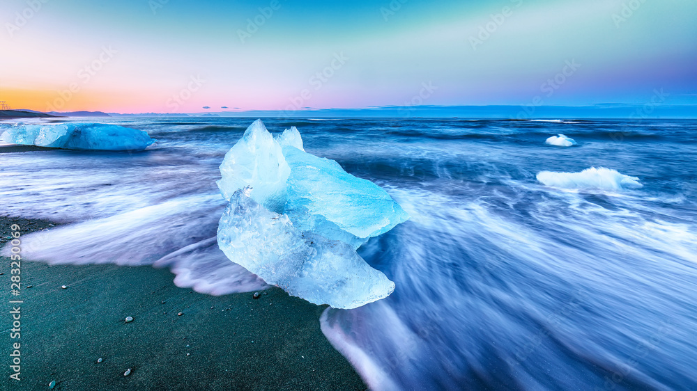 Incredible pieces of the iceberg sparkle on famous Diamond Beach at  Jokulsarlon lagoon during sunset - obrazy, fototapety, plakaty 