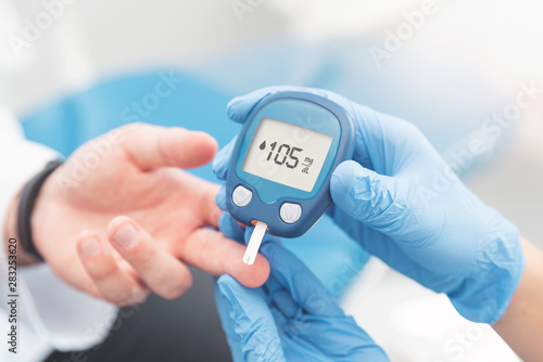 Doctor checking blood sugar level with glucometer photo