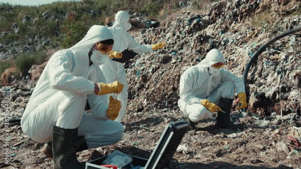 Ecology hazard concept. Male scientists in white suits analyzing