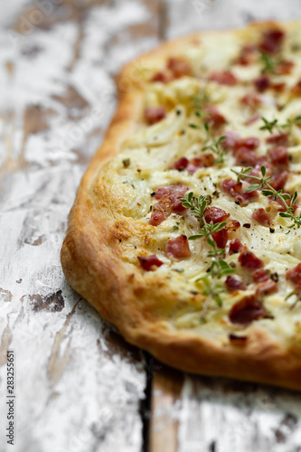 Alsatian tarte flambe with bacon and onions on a wooden background. Flammkuchen, Alsace thin pizza. photo