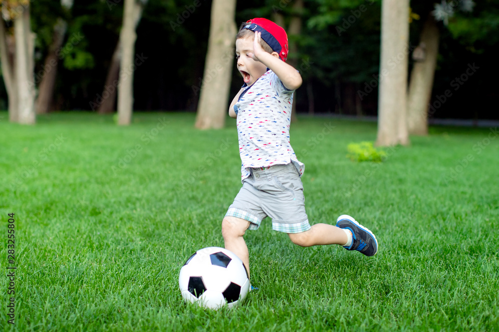 Little boy play soccer at outdoor.Boy running towards ball on a field Little boy play soccer at outdoor.Boy running towards ball on a field