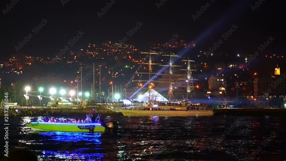 The city is festively lit at night celebrating City Day. Spotlights beautifully illuminate the night city by the sea Yalta 4k The city is festively lit at night celebrating City Day. Spotlights beautifully illuminate the night city by the sea Yalta 4k