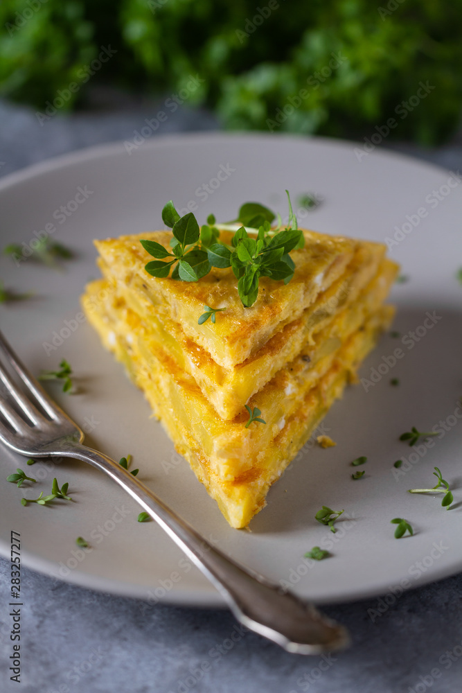 Tortilla, Spanish omelette made with eggs and potatoes. Traditional Spanish tapas or snack served with mini basil. Tortilla, Spanish omelette made with eggs and potatoes. Traditional Spanish tapas or snack served with mini basil.
