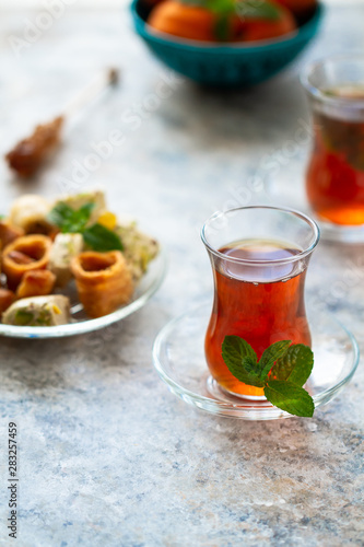 Different oriental sweets on glass plate and turkish tea cups. Baklava,halva,apricots.